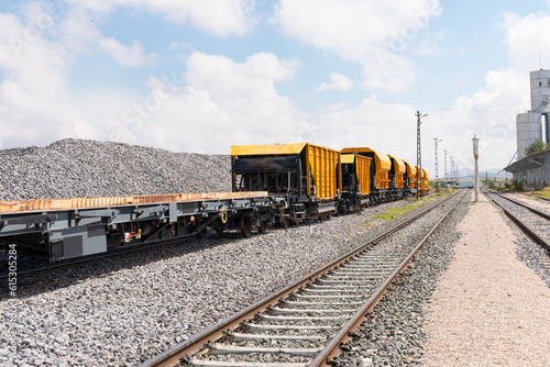 Freight train wagons with pebbles - Trains with special platforms for transporting railway rails