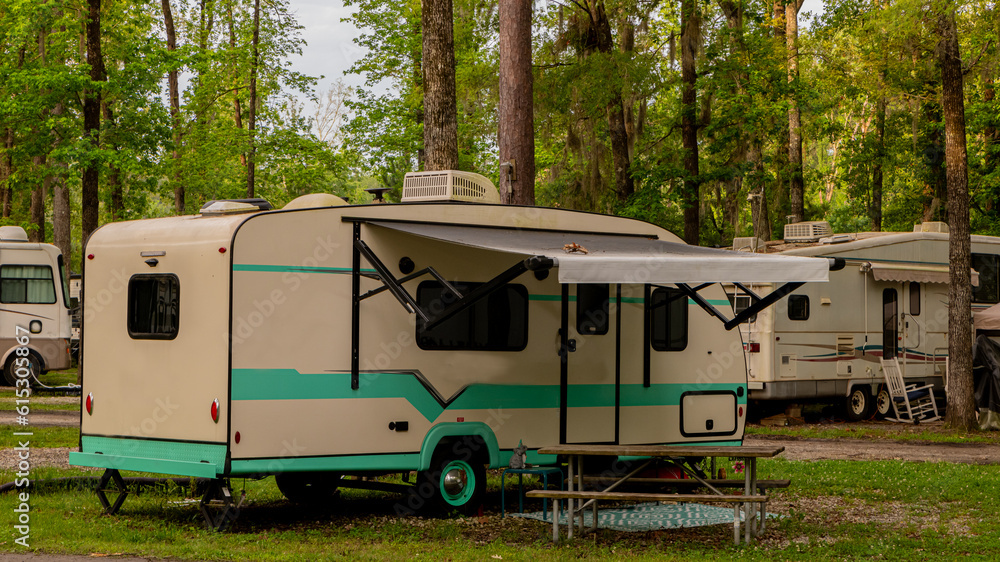 Rv trailer parked on grass under trees 