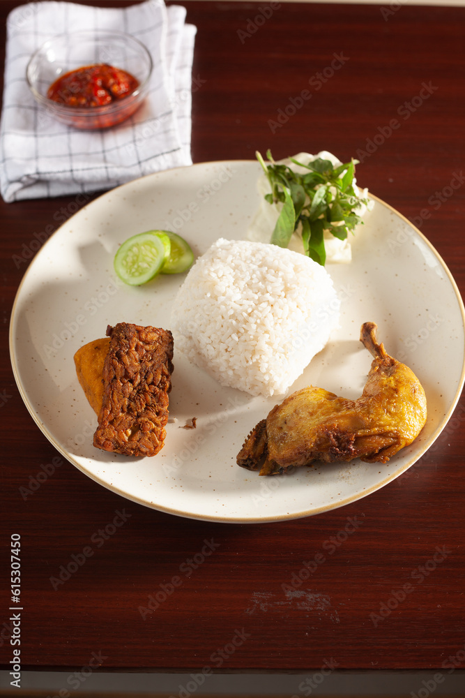 Indonesian Fried Chicken served with tofu, tempe, tomatos, cucumber and rice.