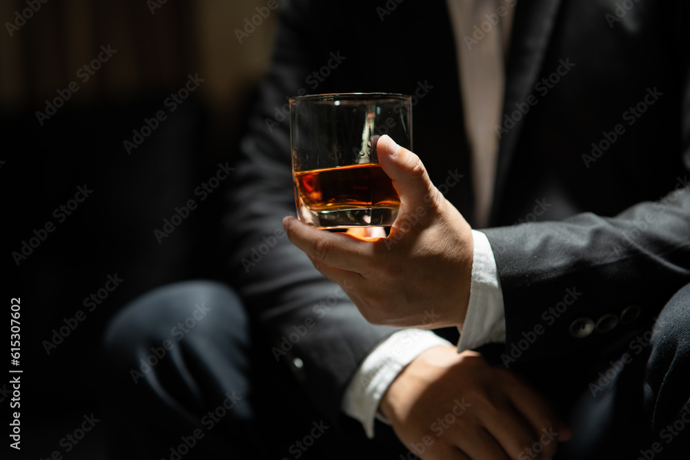 Businessman sitting Holding a Glass of Whiskey Drink Whiskey in the liquor store room Businessman sitting Holding a Glass of Whiskey Drink Whiskey in the liquor store room