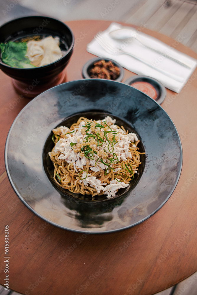 Mie ayam (noodles with chicken, meatballs, dumplings and vegetables) is a popular street food in Indonesia. Blurred background. Close up. Selective focus Mie ayam (noodles with chicken, meatballs, dumplings and vegetables) is a popular street food in Indonesia. Blurred background. Close up. Selective focus