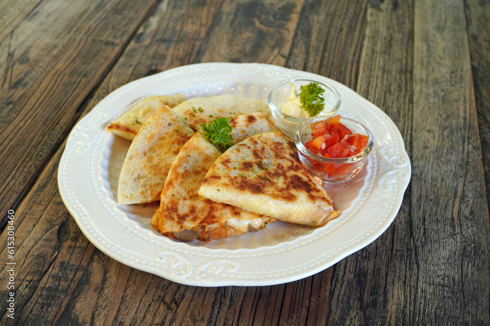 Quesadilla is a Mexican dish consisting of a tortilla that is filled primarily with cheese, and sometimes meats, spices, and other fillings, and then cooked on a griddle or stove. Selective focus