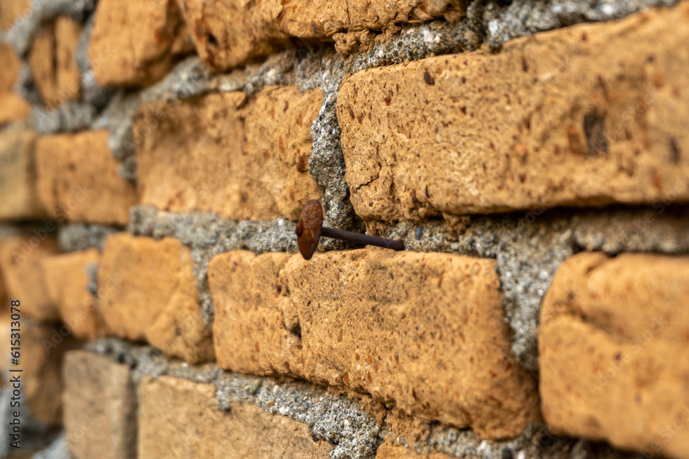 Fototapeta premium Old brickwall background. A nail hammered on red brickwall.