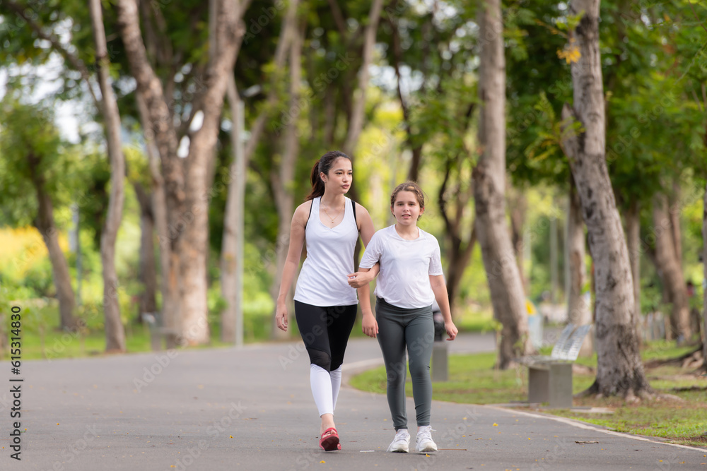 Young female and little girl with walking exercises in the city park Young female and little girl with walking exercises in the city park