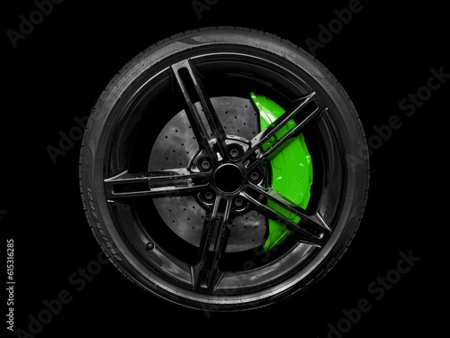 Car alloy wheel and tyre isolated on black background. New alloy wheel with tire and red carbon ceramic brakes. Alloy rim isolated. Car wheel disc. Car spare parts.