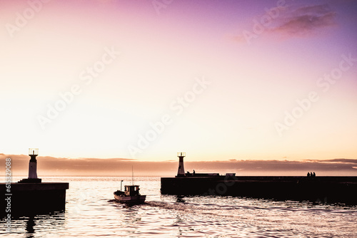 Boat leaving harbor in sunrise © Christelle