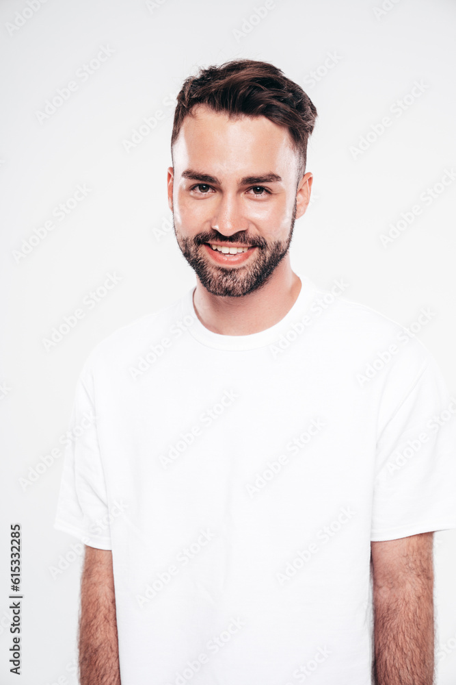 Fototapeta premium Portrait of handsome smiling stylish hipster lambersexual model. Sexy man dressed in white T-shirt and jeans. Fashion male isolated on white background in studio