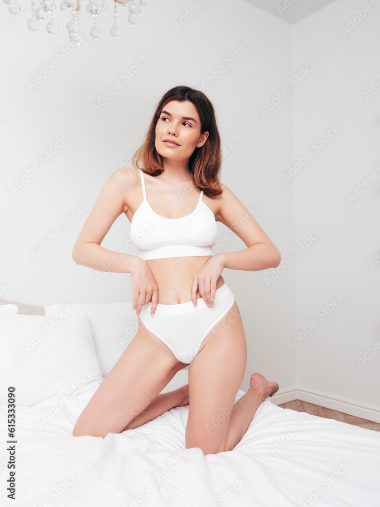 Attractive and relaxed seductive young woman with slim body wearing white underwear. Sexy smiling model lying on sheets in the bedroom at home in the early morning in lingerie. Happy female in bed Attractive and relaxed seductive young woman with slim body wearing white underwear. Sexy smiling model lying on sheets in the bedroom at home in the early morning in lingerie. Happy female in bed