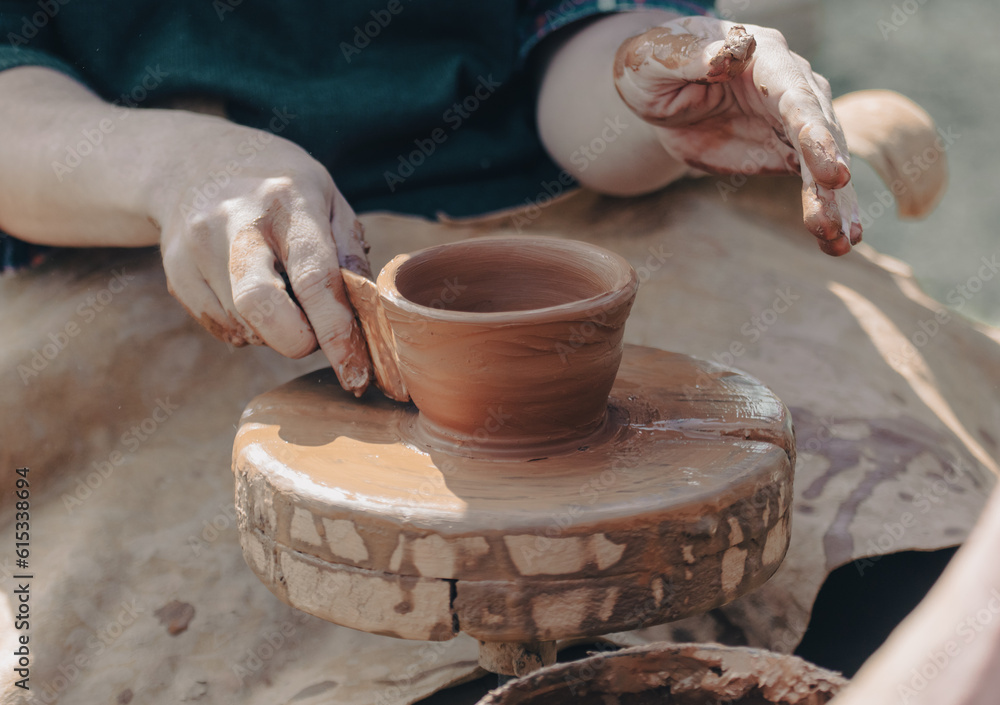 hands of a potter, creating an earthen jar on a pottery wheel