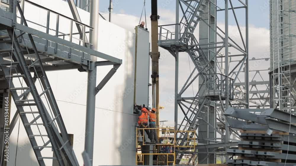 Builders install a concrete wall. A construction crane lifts a concrete wall. Work and construction. Builders install a concrete wall. A construction crane lifts a concrete wall. Work and construction.