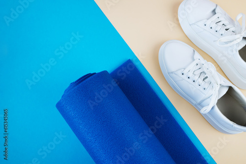 Top view photo of white sneakers and fitness mat.