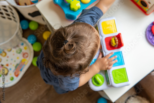 Infant baby playing with colorful animal toys. toddler boy playing with toys at nursery, daycare or kindergarten while standing. Child with educational toys, Early development and education. Top view