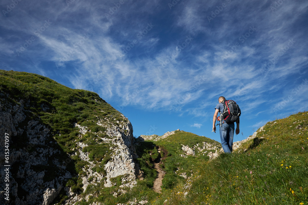 Fototapeta premium man hiking in the mountains with backpack on trails