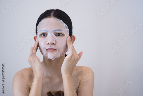 Beautiful Asian woman use a sheet mask on her face.