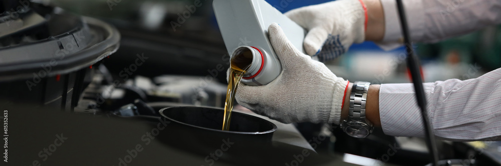 Closeup of experienced mechanic checking and pouring oil into special hole in car. Changing oil in car engine concept
