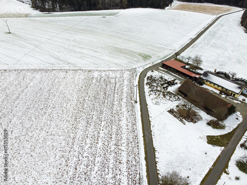 Drone shot of snowy agricultural snowy fields in Bavaria on a cloudy day