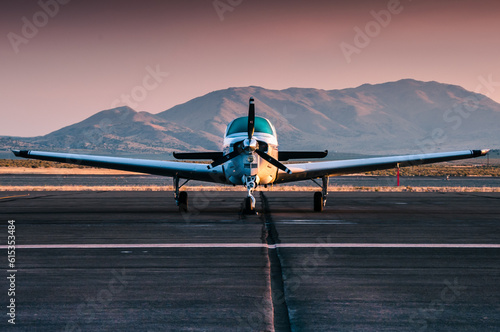 Small general aviation propeller plane parked on an airport in the desert. Photographed during sunrise.