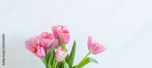 Fototapeta Naklejka Na Ścianę i Meble -  Pink tulips bouquet in glass vase on white background copy space