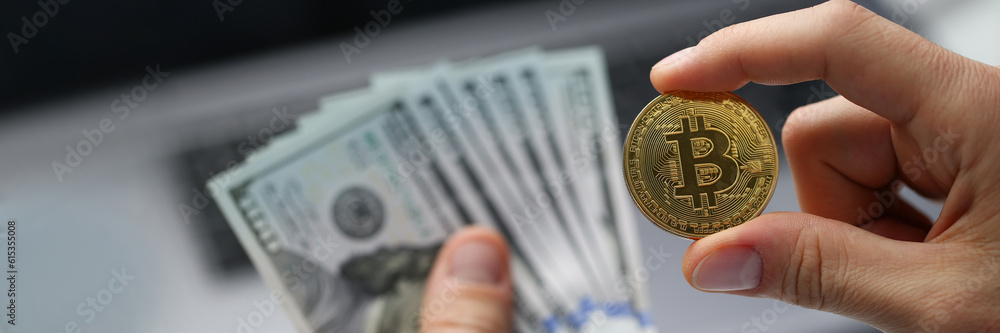 Man hand holds one hundred dollar bills and golden bitcoin coin. Cryptocurrency income and financial investments Man hand holds one hundred dollar bills and golden bitcoin coin. Cryptocurrency income and financial investments