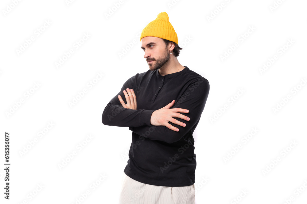 successful 30s authentic brunet male adult in black sweater and yellow cap on white background with copy space