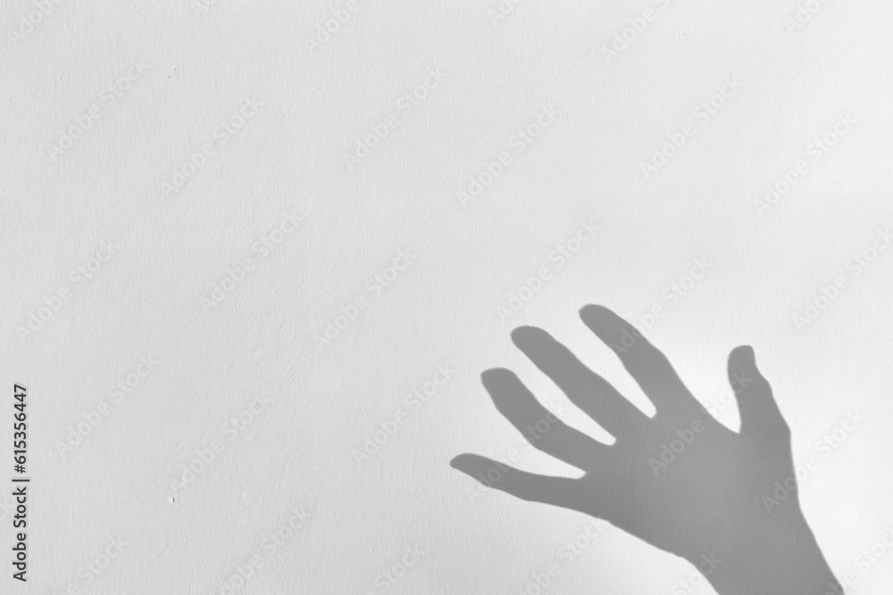 Shadow silhouette of creepy hand on gray background, copy space, noise
