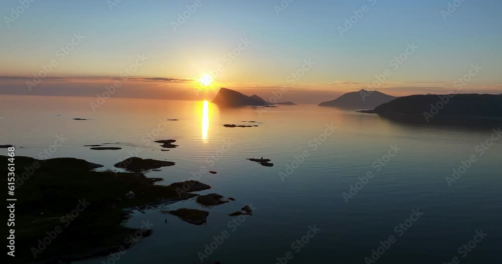 Drone shot rising over small isles, toward the midnight sun above the Haja island, in Troms, Norway Drone shot rising over small isles, toward the midnight sun above the Haja island, in Troms, Norway