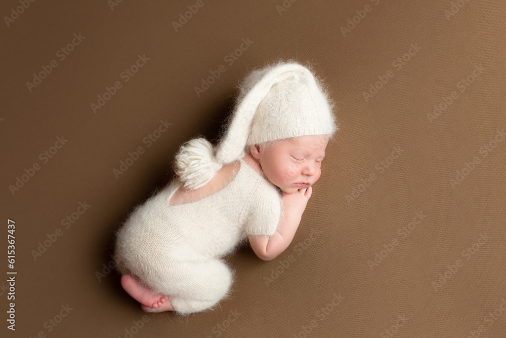 a newborn baby lies on his stomach in a knitted suit. lifestyle. first photo session of a newborn. a little boy a newborn baby lies on his stomach in a knitted suit. lifestyle. first photo session of a newborn. a little boy