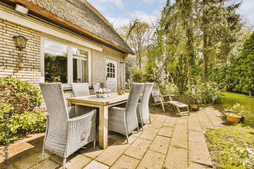 a table and chairs on a patio with a thatched roof in the background  surrounded by lush green trees