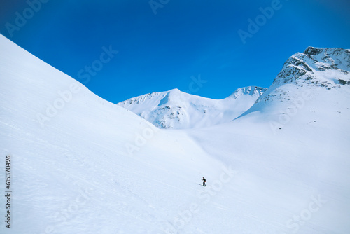 Wide open shot of lonely figure of man walk up mountain slope during mountaineering adventure hike or ski tour. Outdoors winter activity in wilderness © BublikHaus