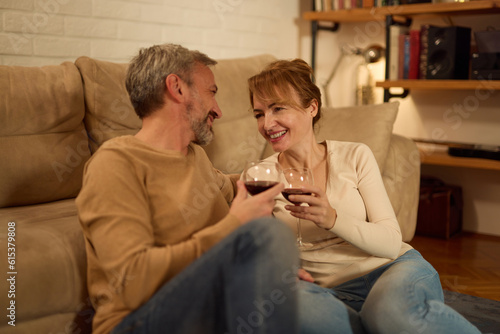 Romantic mature couple relaxing at home and drinking red wine