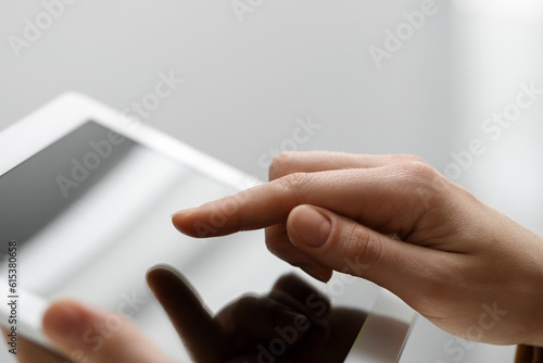 Closeup view of woman using modern tablet on light grey background