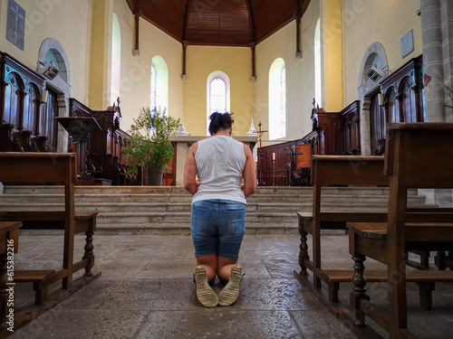 Mulher crente ajoelhada a rezar em frente ao altar num ato de fé photo