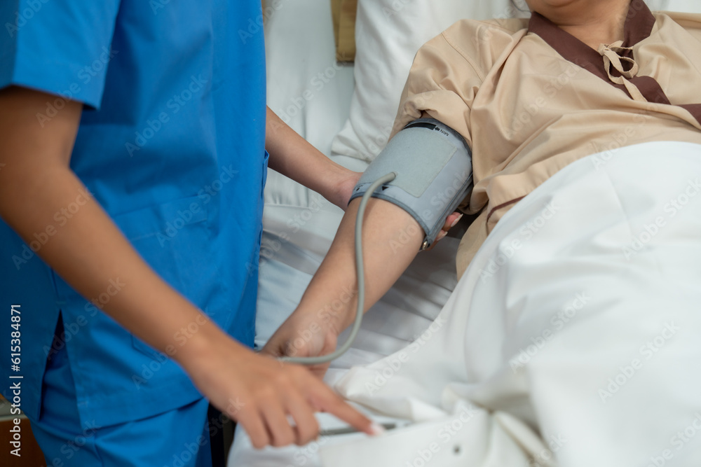 Doctor and nurse measuring blood pressure of patient in recovery room after treatment Doctor and nurse measuring blood pressure of patient in recovery room after treatment
