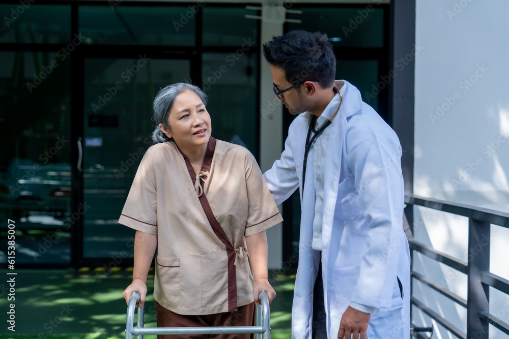 Obraz premium Asian elderly woman walking with walker under close supervision of physiotherapist in rehab center