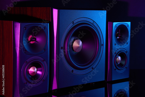 Multimedia acoustic sound speakers with neon lighting. Sound audio system with two satellites and subwoofer on dark background.