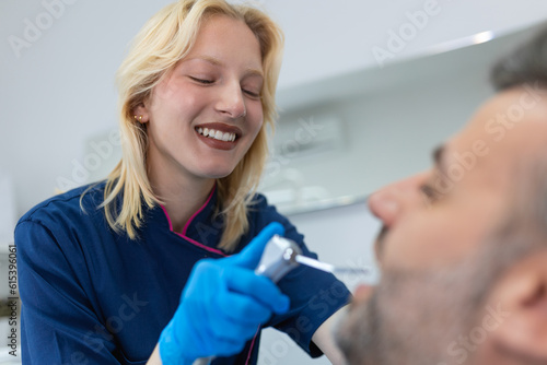 Image of satisfied man sitting in dental chair at medical center while professional doctor fixing his teeth
