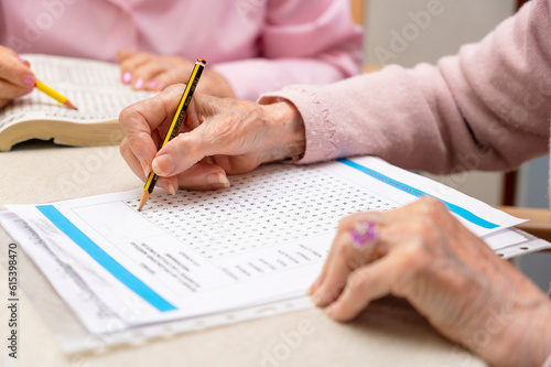 Hands of senior people solving together a word search quiz at nursing home. High quality photo