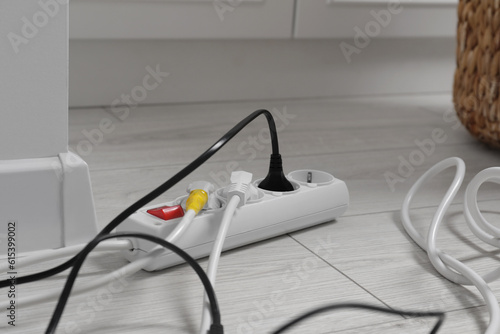 Extension cord with electrical plugs on white floor indoors, closeup