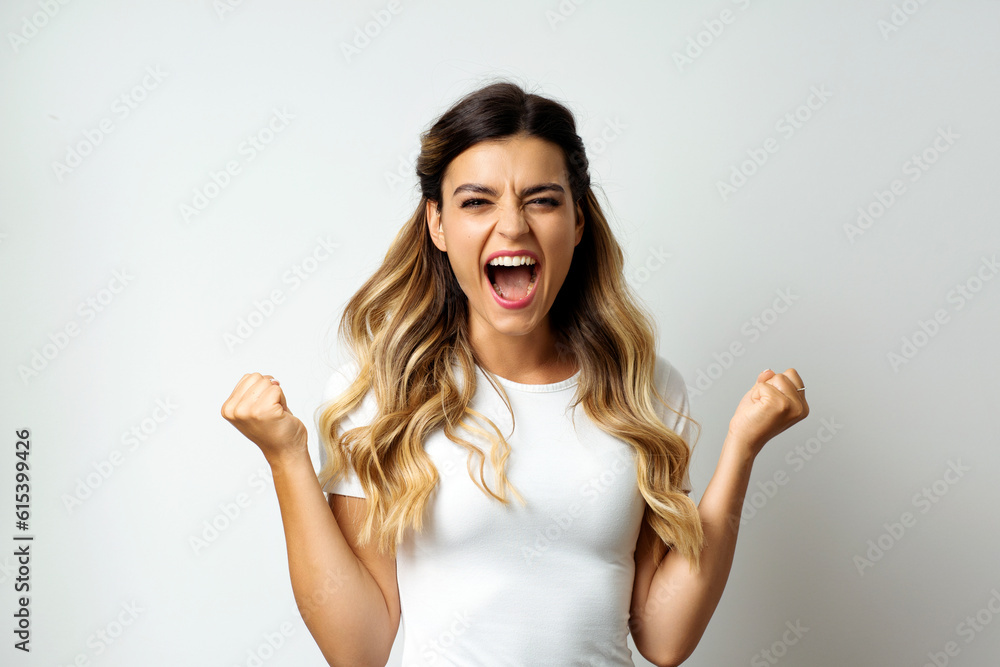 Surprised young woman screaming with hands raised, fists