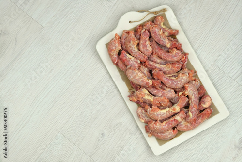 Chicken necks on a ceramic board on wood background. Chicken raw meats. Top view.