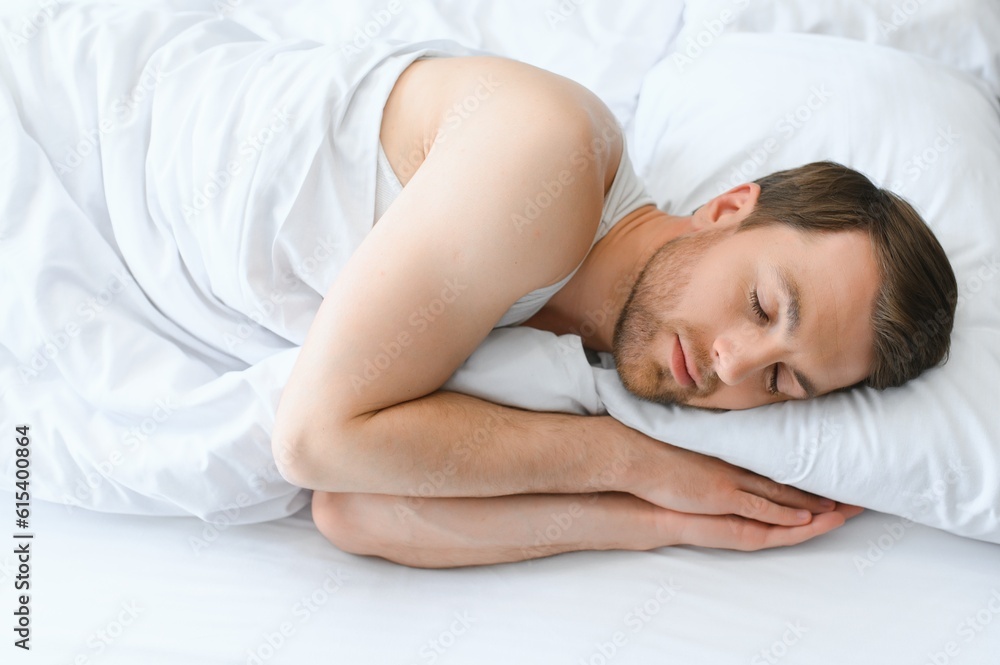Handsome man sleeping under soft blanket in bed at home Handsome man sleeping under soft blanket in bed at home