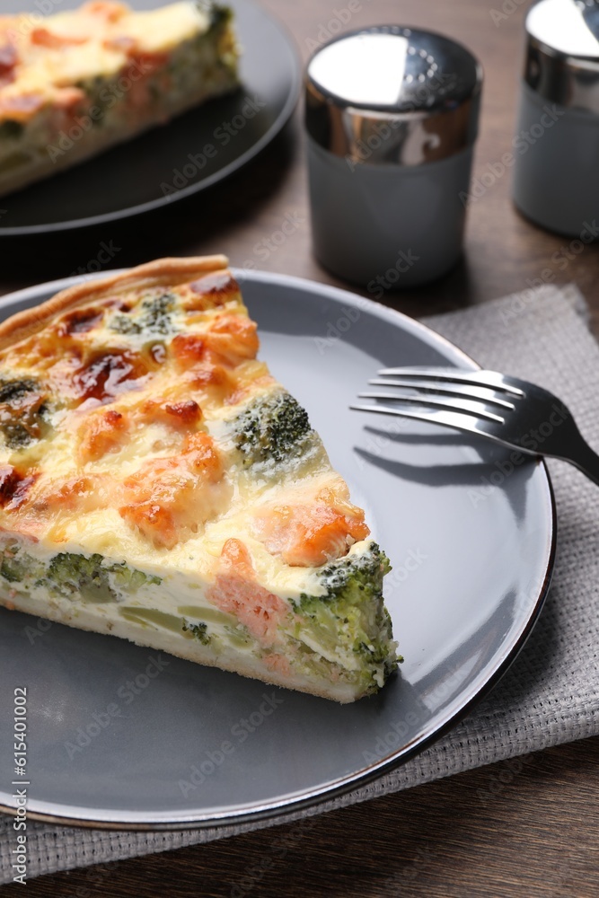 Piece of delicious homemade salmon quiche with broccoli and fork on wooden table Piece of delicious homemade salmon quiche with broccoli and fork on wooden table