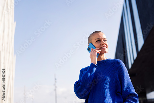 фотографія confident young woman with buzz cut in blue sweater talking happy on mobile phon