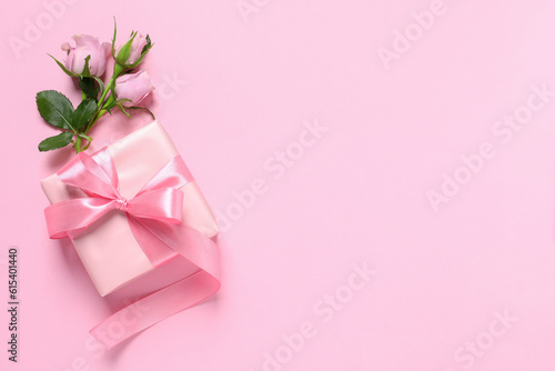 Gift box and beautiful rose flowers on pink background, flat lay. Space for text © New Africa