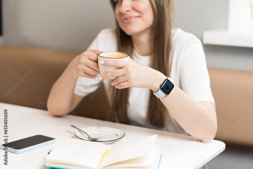 Close-up of the hands of a freelancer girl with coffee in a cozy cafe. Freelance concept. Close-up of the hands of a freelancer girl with coffee in a cozy cafe. Freelance concept.
