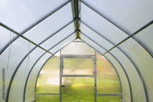 Close-up view of farm polycarbonate greenhouse or hothouse for growing eco organic fruits, vegetables or plants.

Farming, gardening and horticulture concept.