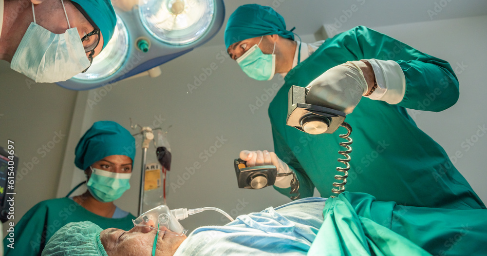 Team of surgery doctor using defibrillator pump chest heart patient to