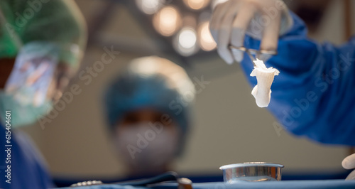 Foto Hand of surgery doctor in Operating Room hold operating plier forceps tweezer pinch gauze and Dip piece of gauze into the solution wound healing potion in Operating theater