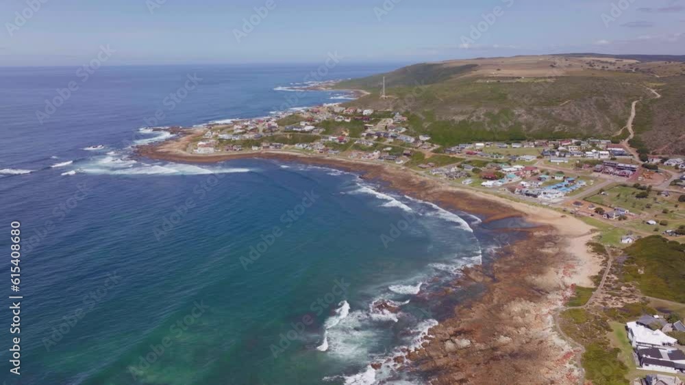 South Africa aerial drone cinematic beach small surf town Garden Route Still Bay Jeffreys Bay homes and buildings waves crashing on reef people walking street late morning afternoon backward movement South Africa aerial drone cinematic beach small surf town Garden Route Still Bay Jeffreys Bay homes and buildings waves crashing on reef people walking street late morning afternoon backward movement