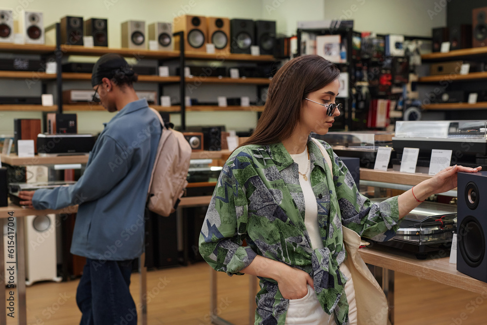 Waist up portrait of two young people looking at tech in music store
